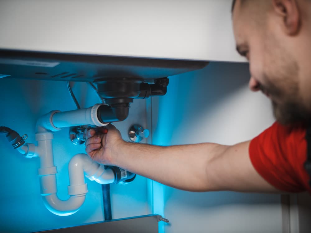 Artisan plombier au travail sur installation sous évier